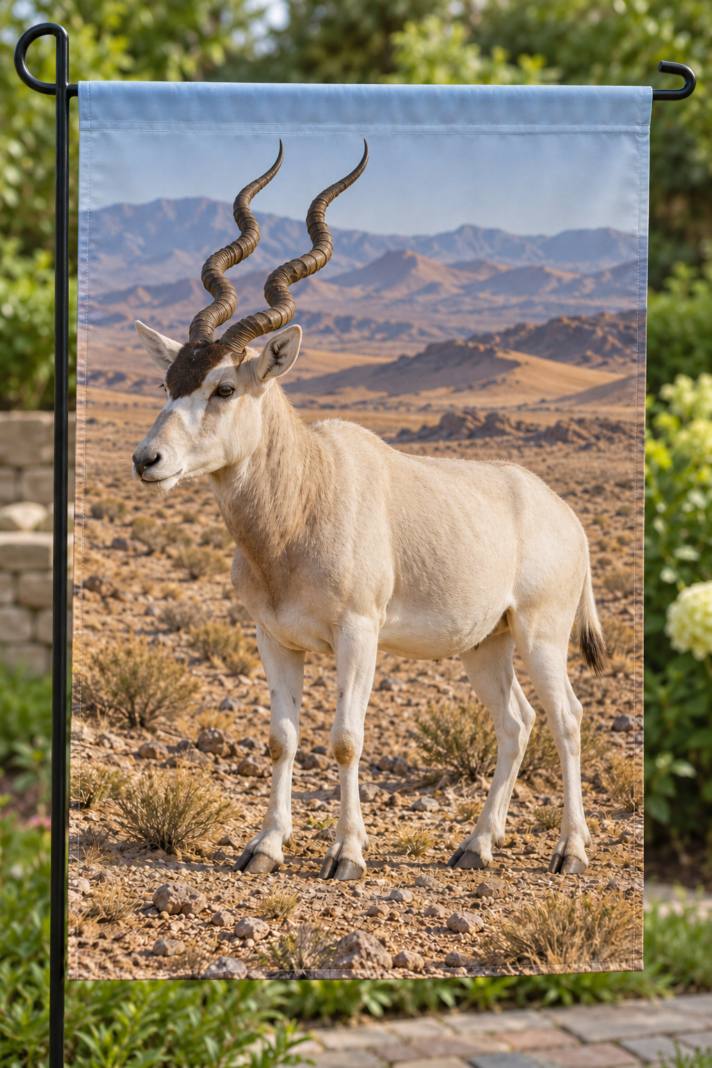 Addax with spiralling horns before deep layered desert printed on a complete hemmed garden flag
