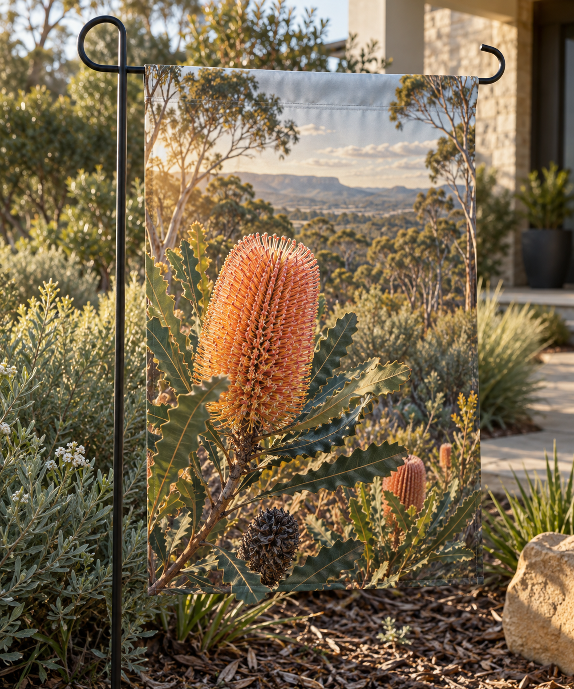 Pink-orange firewood banksia flower spike and serrated leaves before receding woodland printed on a rectangular garden flag