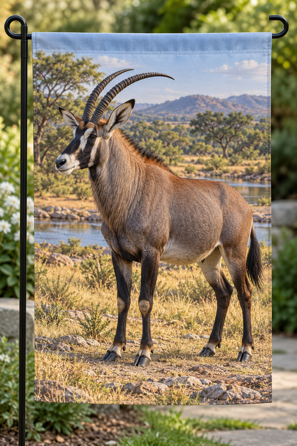 Roan antelope beside a deep wooded savanna waterway printed on a complete hemmed garden flag