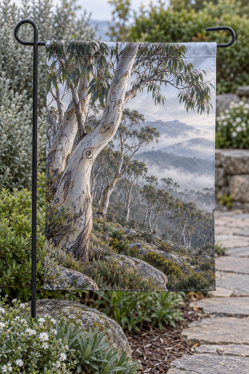 Smooth pale snow gum trunks and narrow leaves before misty rocky mountains printed on complete garden flag