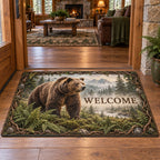 Brown bear doormat with ferns, forest water and misty mountains in a rustic lodge setting.