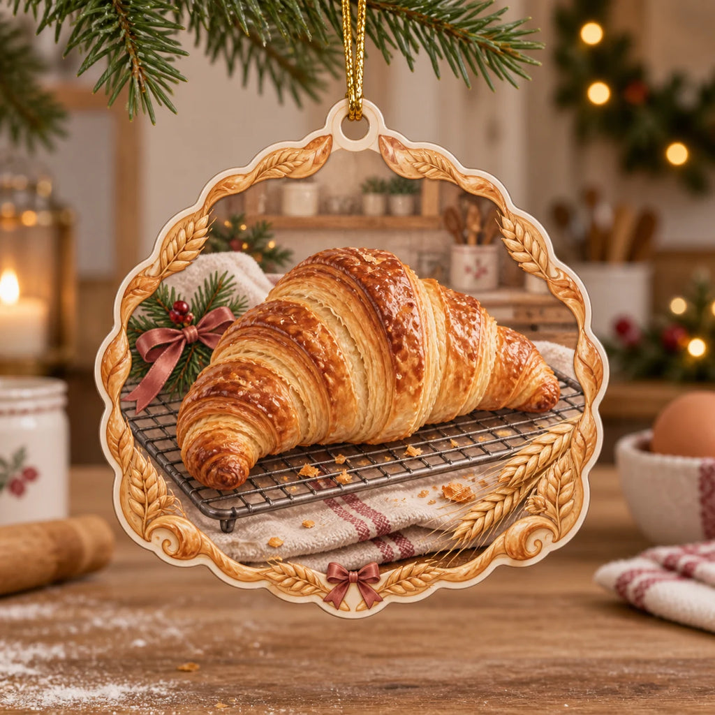 Croissant christmas ornament with golden laminated pastry on cooling rack, striped linen, wheat accents and cozy baking kitchen.