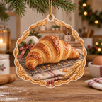 Croissant christmas ornament with golden laminated pastry on cooling rack, striped linen, wheat accents and cozy baking kitchen.