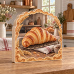 Croissant wooden block with golden laminated pastry on cooling rack, striped linen, wheat accents and cozy baking kitchen.