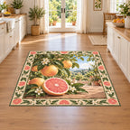 Grapefruit area rug with pink cut fruit, whole grapefruit, glossy green leaves and cream botanical edging in a bright kitchen.