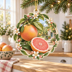 Grapefruit christmas ornament with pink cut fruit, whole grapefruit, glossy green leaves and cream botanical edging in a bright kitchen.