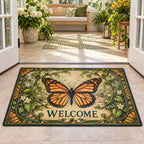 Doormat showing a monarch butterfly with four orange-and-black wings, curling green vines and cream garden details with WELCOME lettering.